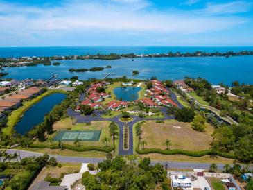 Aerial view of waterfront community with tennis court and lush landscaping at 758 Sarabay Rd # 5, Osprey, FL 34229