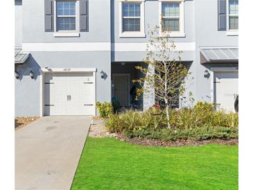 Front view of townhome with a 2-car garage and landscaped lawn at 14339 Easy Goer St, Ruskin, FL 33573