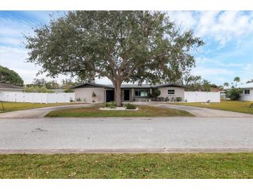 Ranch style home with mature landscaping and a large driveway at 2430 Sunnyside Ln, Sarasota, FL 34239
