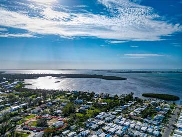 Aerial view showing a waterfront property with surrounding houses and lush greenery at 4420 102Nd W St, Bradenton, FL 34210