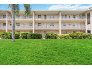 Condo building with lush landscaping and a manicured lawn at 3987 Maceachen Blvd # 123, Sarasota, FL 34233