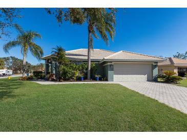 Single-story house with a landscaped lawn, palm trees, and a two-car garage at 7203 41St E Ct, Sarasota, FL 34243