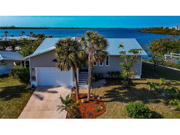 Single-story home with metal roof, two palm trees, and waterfront views at 10428 Marion St, Englewood, FL 34224