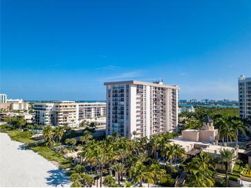 Aerial view of beachfront condo building with pool and lush landscaping at 1212 Benjamin Franklin Dr # 305, Sarasota, FL 34236