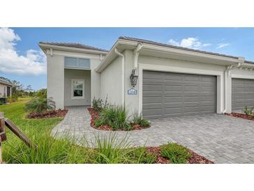 Single-story home with gray garage door and paved walkway at 12649 Palatka Dr, Venice, FL 34293