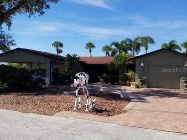 Single-story home with attached garage and carport, landscaping, and palm trees at 1420 Lemon Bay Drive Dr, Englewood, FL 34223