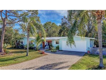 Light blue house with a paved driveway, palm trees, and a white picket fence at 2338 Lynn St, Sarasota, FL 34231