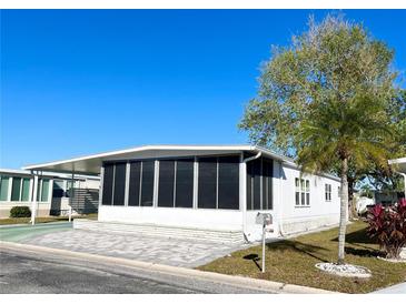 White mobile home with screened porch, paved patio, and landscaping at 3411 Spanish Oak Ter, Sarasota, FL 34237