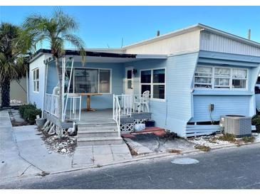 Light blue mobile home with covered porch, steps, and palm tree at 3710 Gulf Of Mexico Dr # G-6, Longboat Key, FL 34228