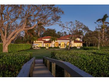 Expansive backyard with lush greenery, wooden footbridge, and a view of the house at 3930 Red Rock Way, Sarasota, FL 34231