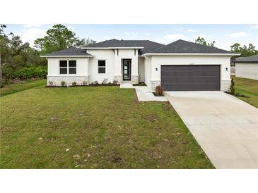 A modern, single-story home with a two-car garage and landscaped lawn at 5595 Delight Ave, North Port, FL 34288