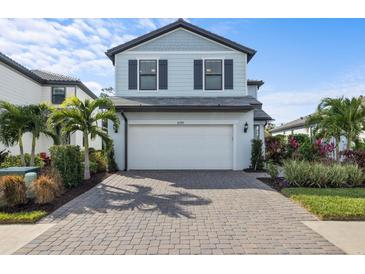 Two-story house with white garage door and landscaped yard at 6299 Crested Eagle Ln, Nokomis, FL 34275