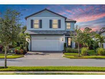 Two-story home with light blue siding, two-car garage, and landscaping at 6299 Crested Eagle Ln, Nokomis, FL 34275