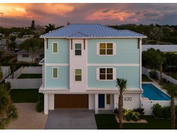 Two-story light teal home with a pool and attached garage at 630 Companion Way, Longboat Key, FL 34228