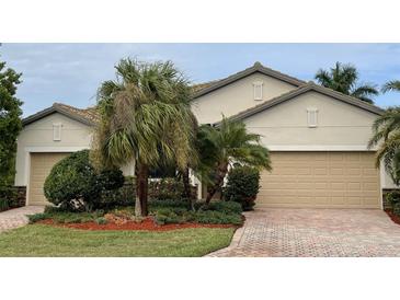 Two-car garage, beige house with landscaping, and a brick driveway at 6442 Willowshire Way, Bradenton, FL 34212