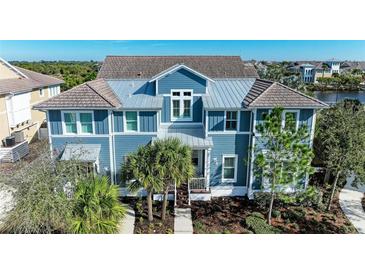 Two-story home with blue siding, metal roof, and palm trees at 307 Compass Point Dr # 101, Bradenton, FL 34209