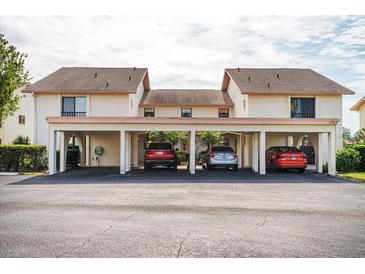 Exterior view of condo building with covered carport and parking spaces for residents at 1767 Lake Pl # 1767A, Venice, FL 34293