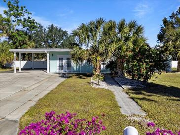 Charming light blue house with carport, landscaping, and walkway at 207 Waterway Ne Cir, Port Charlotte, FL 33952