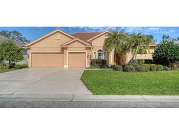 Tan house with tile roof, two-car garage, and lush landscaping at 4881 Flagstone Dr, Sarasota, FL 34238