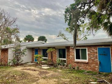 Brick ranch home with a metal roof and blue door at 7820 Midnight Pass Rd, Sarasota, FL 34242