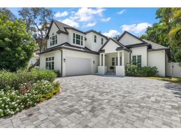 Two-story home with white exterior, gray paver driveway, and landscaping at 2174 Mcclellan Pkwy, Sarasota, FL 34239
