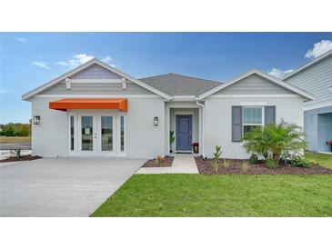 One-story home with gray siding, orange awning, and landscaped yard at 4519 Boxelder Avenue, Parrish, FL 34219