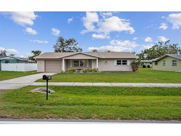 Tan single story house with a neatly landscaped lawn and driveway at 1215 E Venice Ave, Venice, FL 34285