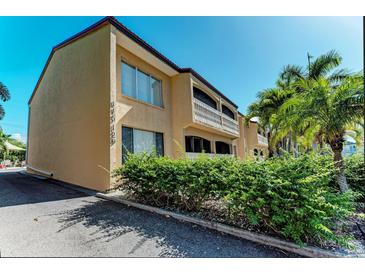 Tan colored building exterior with lush landscaping and palm trees at 129 Tyler Dr # 101, Sarasota, FL 34236