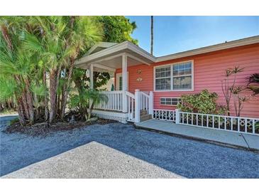 Pink cottage with white trim, front porch, and small yard at 1603 Gulf N Dr # 27, Bradenton Beach, FL 34217