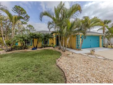 Bright yellow house with teal garage door, landscaping, and palm trees at 3972 Titan St, North Port, FL 34286