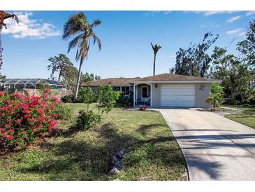 Tan single story home with a large yard, palm trees, and a two-car garage at 5708 Miami Rd, Venice, FL 34293