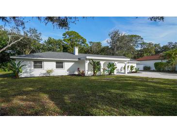 White single-story home with gray roof, landscaped yard, and driveway at 1411 Quail Dr, Sarasota, FL 34231