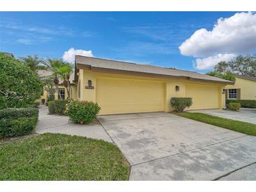 Front view of a yellow house with a two-car garage and landscaped yard at 7146 Lakeside Dr, Sarasota, FL 34243