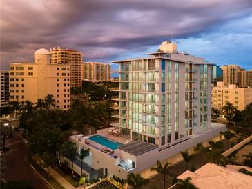 Aerial view of modern building with pool and surrounding cityscape at 111 Golden Gate Pt # 701Ph, Sarasota, FL 34236