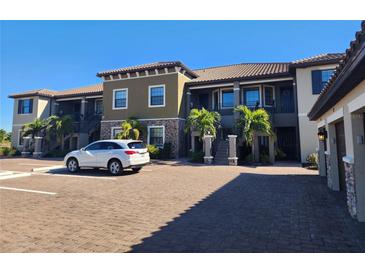 Two-story condo building with attached garages and paved parking at 12410 Osorio Ct # 103, Sarasota, FL 34238