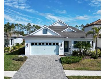 White house with light blue garage door, paver driveway, and landscaping at 13153 Steinhatchee Loop, Venice, FL 34293