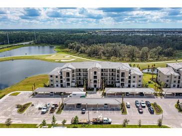 Aerial view of a modern apartment building with parking and a golf course nearby at 18114 Gawthrop Dr # 404, Bradenton, FL 34211