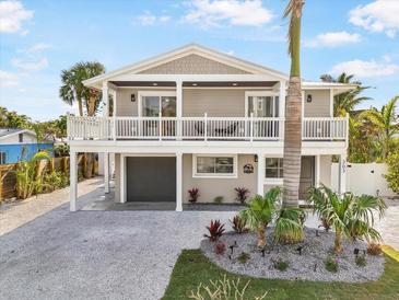 Two-story house with a white balcony, gray siding, and landscaped yard at 203 72Nd St, Holmes Beach, FL 34217