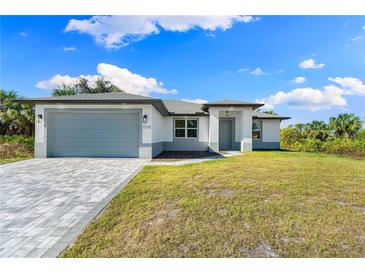 New single-story home with gray garage door, paver driveway, and landscaped lawn at 2133 Selover Rd, North Port, FL 34287