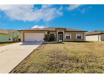 Tan house with white garage door and landscaping at 22419 Bette Ave, Port Charlotte, FL 33954