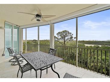 Spacious screened balcony with outdoor dining furniture and scenic nature views at 385 N Point Rd # 402, Osprey, FL 34229