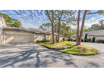 Exterior view of a charming villa with a two-car garage and lush landscaping at 4372 Woodmans Chart # 143, Sarasota, FL 34235