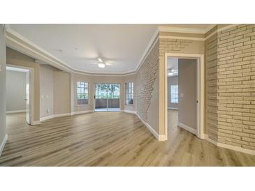 Spacious living room with hardwood floors and brick accent wall at 5180 Northridge Rd # 101, Sarasota, FL 34238