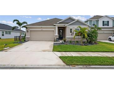 Two-story house with gray siding, stone accents, and a two-car garage at 11771 Richmond Trl, Parrish, FL 34219