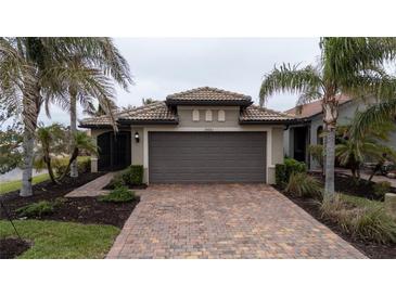 Single-story home with a gray garage door and tile roof, nestled in a landscaped yard at 19261 Isadora St, Venice, FL 34293