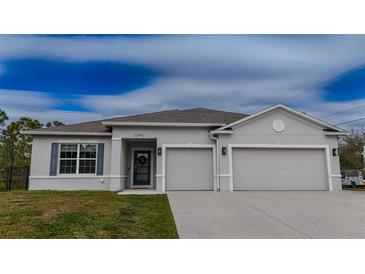 One-story house with gray siding, three-car garage, and a well-manicured lawn at 22490 Madelyn Ave, Port Charlotte, FL 33954