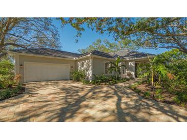 Single-story home with a light-colored exterior, a paved driveway, and lush landscaping at 32 Bayhead Ln, Osprey, FL 34229