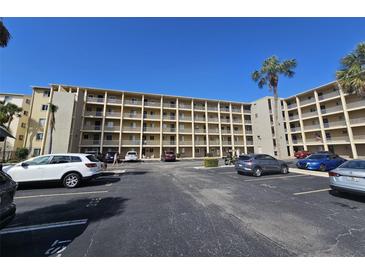 Multi-story condo complex with multiple balconies and parking lot featuring various parked cars on a sunny day at 3682 Lake Bayshore Dr # K402, Bradenton, FL 34205