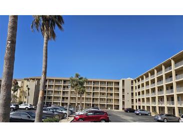 Condo building showing tan exterior, multiple balconies, parking lot and palm trees in the background on a sunny day at 3682 Lake Bayshore Dr # K402, Bradenton, FL 34205