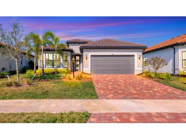 Single-story home with gray garage door and brick driveway at 7432 Summerland Cv, Lakewood Ranch, FL 34202